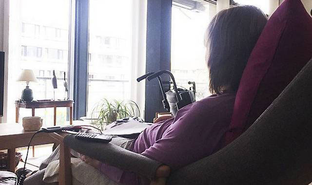 Ældre kvinde med parkinsons sidder i stol og kigger ud af vinduet