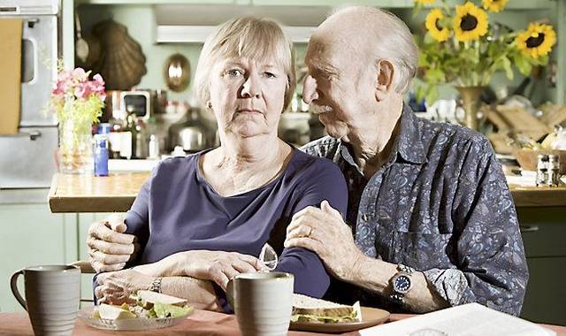 Ældre bedrøvet ægtepar sidder ved spisebordet